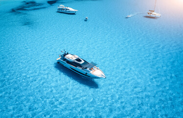 Aerial view of beautiful luxury yacht and sailboats in blue sea
