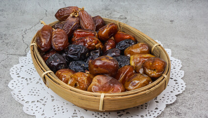 Set of various dates in bamboo basket over cement texture background. selective focus