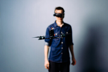Engineer holding fpv racing kamikaze drone bomber on blue background. Starting motors