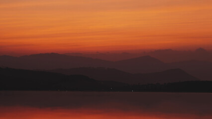 Fototapeta na wymiar Passenger plane landing on background beautiful sunset and reflecting in water