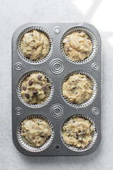 Chocolate chip muffin batter in a lined cupcake tin, vanilla and chocolate chip muffin batter, process of making muffins