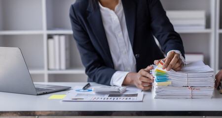 Business Employee Asian woman hand working in Stacks paper files for searching and check unfinished...