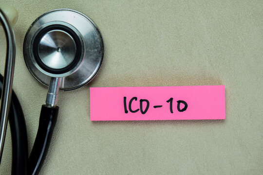 Concept of ICD-10 write on sticky notes with stethoscope isolated on Wooden Table.