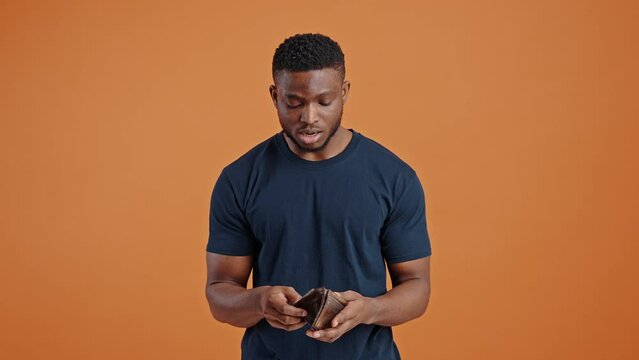 Young dark-skinned man expressing sudden shock and throws his leather purse while find it empty