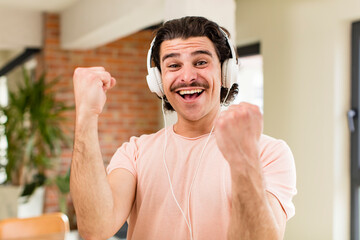 young handsome man listening music with headphones at home at home interior