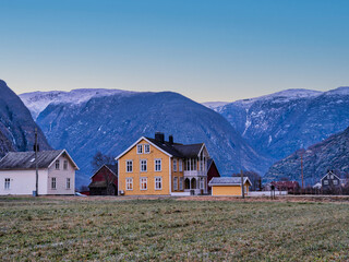 Traditional Norwegian colourful houses in rural Norway with snow-capped mountain in the background