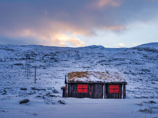 Traditional Norwegian Sod roof house in rural Norway during winter with colourful cloud sky