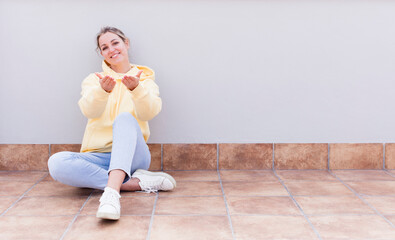 pretty caucasian sitting  woman smiling happily with friendly, confident, positive look, offering and showing an object or concept