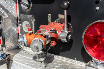 Close up view of rear fire truck has large water control valves and lever for connecting hoses to