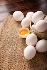 Many white chicken eggs and yolk on rustic wooden table. Very popular nutritious and economic food product.