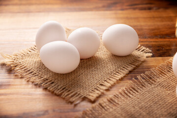 Many white chicken eggs on rustic wooden table. Very popular nutritious and economic food product. Closeup image.