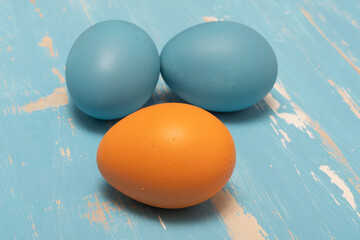 Eggs symbolizing the Easter holiday in blue and orange color on a background of aged wood