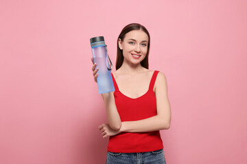 Beautiful young woman with transparent bottle for water on pink background