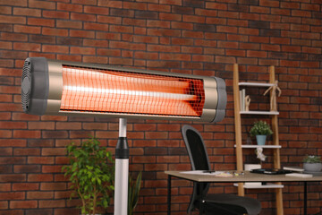 Electric infrared heater near brick wall in stylish room