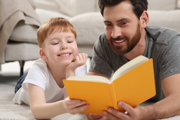 Father reading book with his child on floor at home, closeup