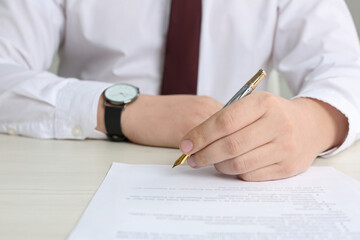 Notary signing document at wooden table, closeup