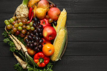 Different fresh vegetables and fruits on black wooden table, top view with space for text. Farmer harvesting