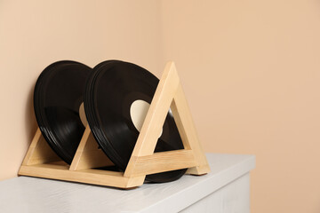 Vinyl records on white wooden drawer dresser near beige wall, space for text