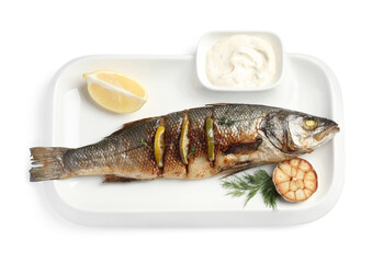 Plate with delicious roasted sea bass fish, garlic, slice of lemon and sauce on white background,...