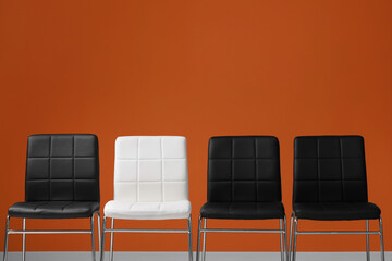 Black chairs with white one near orange wall, space for text. Recruiter searching employee