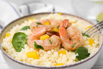 Tasty couscous with shrimps, bell pepper and basil on white table, closeup