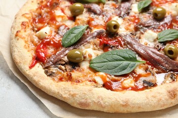 Tasty pizza with anchovies, basil and olives on white table, closeup