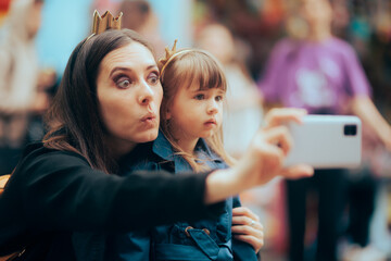 Funny Mom and Daughter Taking Selfies at Public Event. Mother and child having fun capturing candid...