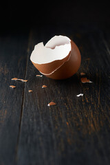 brown egg shell broken or crack with pieces scattered on the surface, isolated on rustic black...