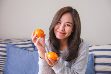Portrait image of a young woman holding oranges in hands