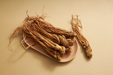 Top view of angelica sinensis roots on wooden dishes on brown background. This is considered a type...