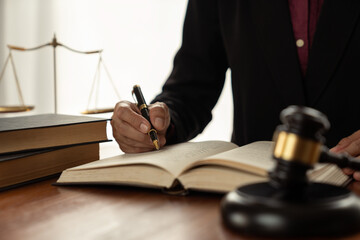 female lawyer, law adviser, businesswoman sitting and reading with finger pointing at legal code information. Business agreement on book working with scales and hammer in office.
