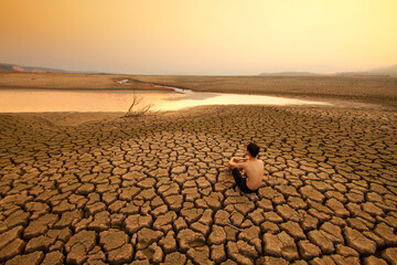 Young man sit on dry cracked earth near drying river or lake metaphor Water crisis, Drought and...