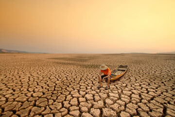 Young man sit on wooden boat with landscape of dry lake or river metaphor climate change, Drought...