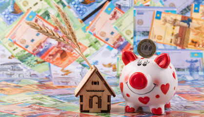 Wheat ears, miniature house, piggy bank and Kazakh currency - tenge
