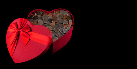 Gift box filled with american coins in the form of a heart on a black background