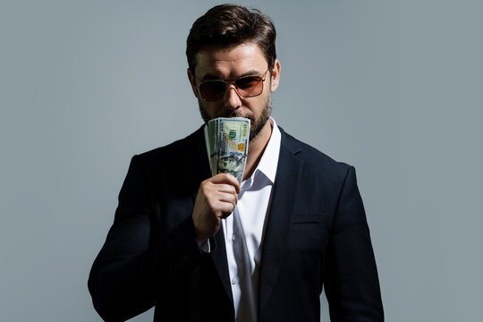 Man showing cash money in dollar banknotes. Portrait of business man isolated on gray studio background. Successful winner celebrating success or victory with money bills.