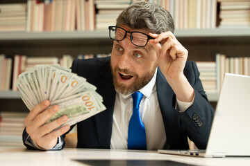 Portrait funny amazed excited business man holding cash dollar bills in office. Big luck, banner....