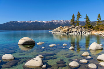 Rocky Blue Lake - A calm Spring day view of a crystal-clear rocky cove at Sand Harbor of Lake...