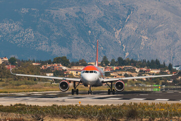 Fototapeta premium View of modern passenger plane aircraft on an runway airfield ready to take off, airstrip with commercial airplane before take off or after landing, airliner with mountains in a summer day