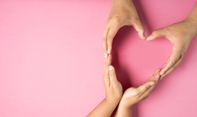 Adult hands made heart symbol on pink background , health care, organ donation, family life insurance, world heart day, world health day, praying concept