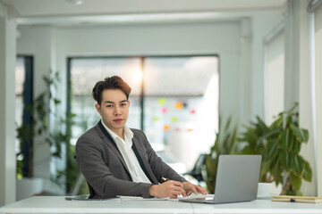 Happy satisfied millennial man using laptop at office workplace, working from home, reading message with good news, thinking, looking at screen, watching online webinar, training, making payment