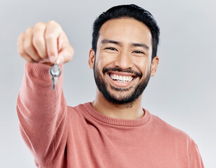 Key, real estate and smile with portrait of man in studio and giving you property, new homeowner or achievement. Rent, pride and purchase with male on white background for house, tenant or investment - obrazy, fototapety, plakaty