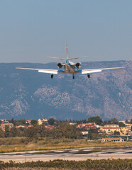 Fototapeta na wymiar View of modern private reactive plane aircraft in flight, business airliner jet airplane before in the air with mountains in the background in a summer sunny day, corporate jet view