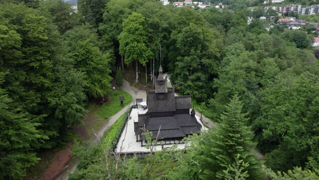 Drone shot around a medieval wooden Christian church building in cloudy Fantoft, Norway
