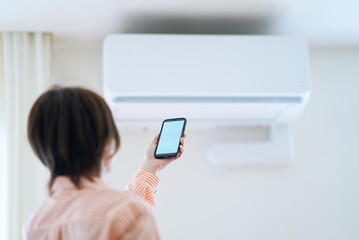 室内でスマートフォンをかざす女性