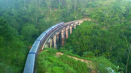 Drone Sri Lanka 4k. Kandy to Ella train on Nine Arch bridge in Sri Lanka. Scenic railway route in tea plantations. South Asia summer tourism.