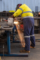 Man wearing full protective equipment angle grinding to effect repairs on some mining equipment