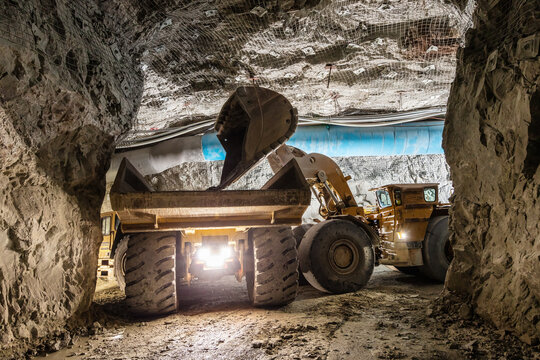 Mining load truck being filled with ore by an excavator underground in a mine site in Australia