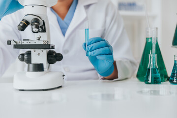 Scientist or doctor wear medical protective mask looking at blood samples under microscope.