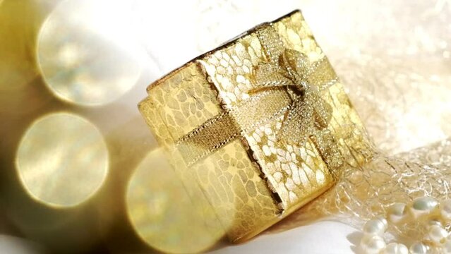 A golden gift box and sniny  golden bokeh. Wedding, Birthday. Luxury ceremony
